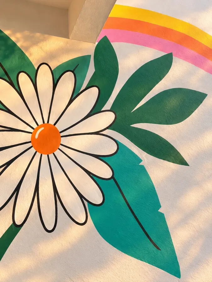 Detalhe de margarida pintada à mão, com contorno preto e miolo laranja